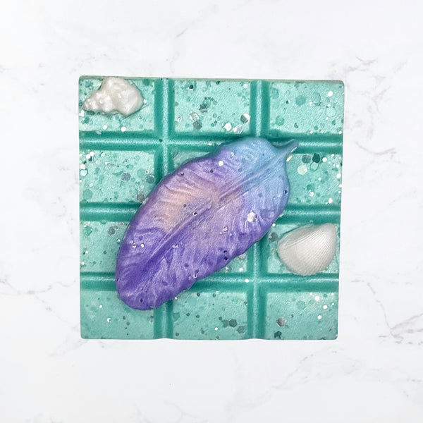Purple feather on a green and white wax melt